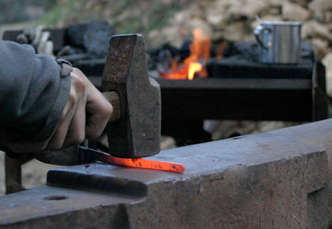 artisan coutelier martelant du métal chauffé 