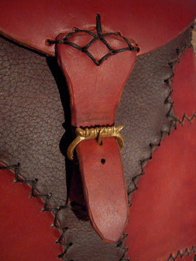 détail d'un sac à main marron et rouge, avec boucle en cuivre moulée