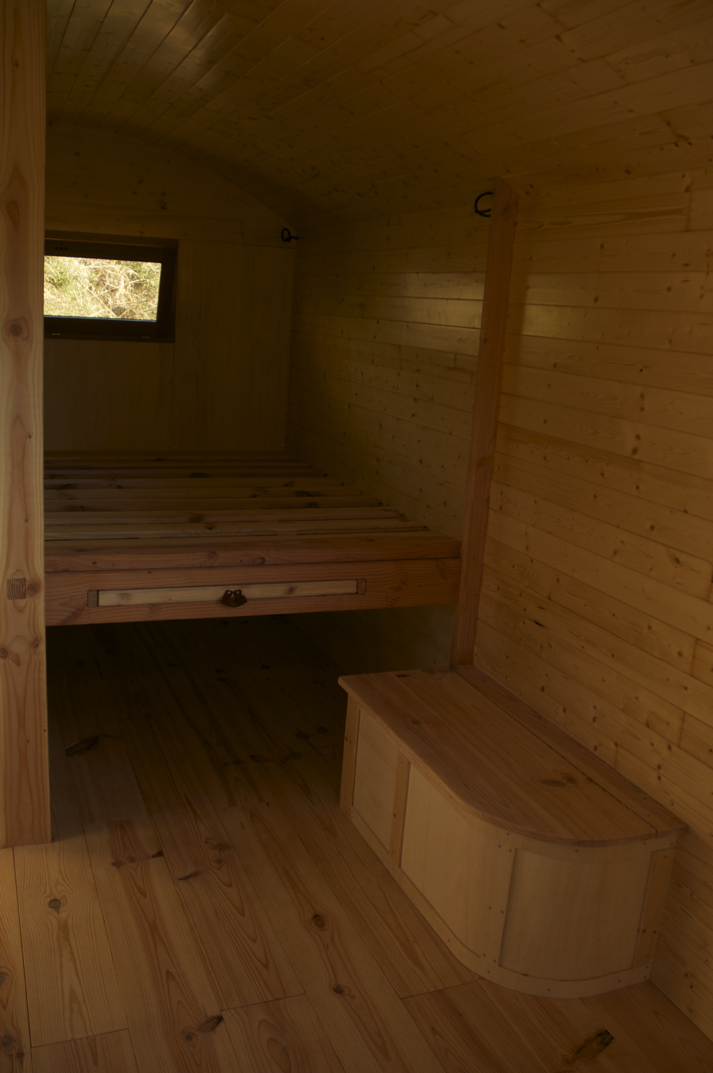 lit et banc en bois dans une roulotte aménagée